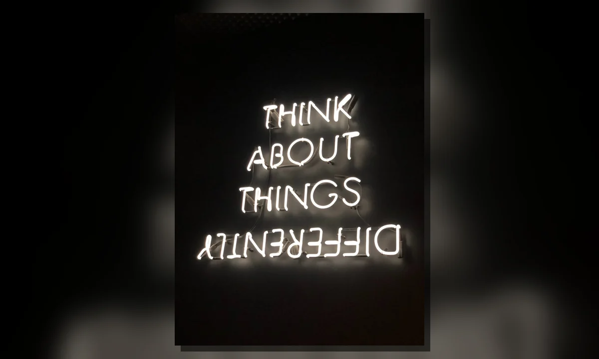 A neon message encouraging readers to think differently before sharing information